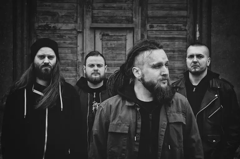 Decapitated band members in a black and white promotional photo, standing in front of an old wooden door.