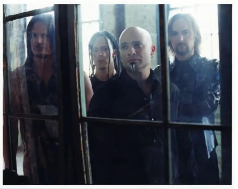 Disturbed band members standing behind an old window, creating a moody and introspective atmosphere.