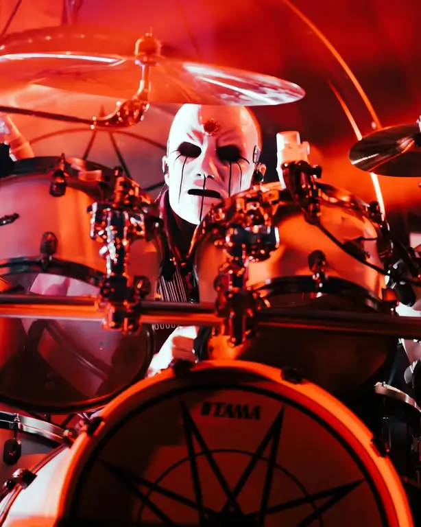 Eloy Casagrande of Slipknot playing drums on stage, surrounded by red lighting.