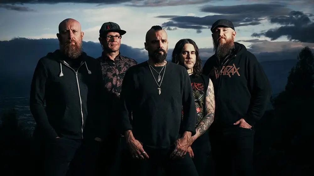 Killswitch Engage band members posing outdoors with a dramatic cloudy sky in the background.