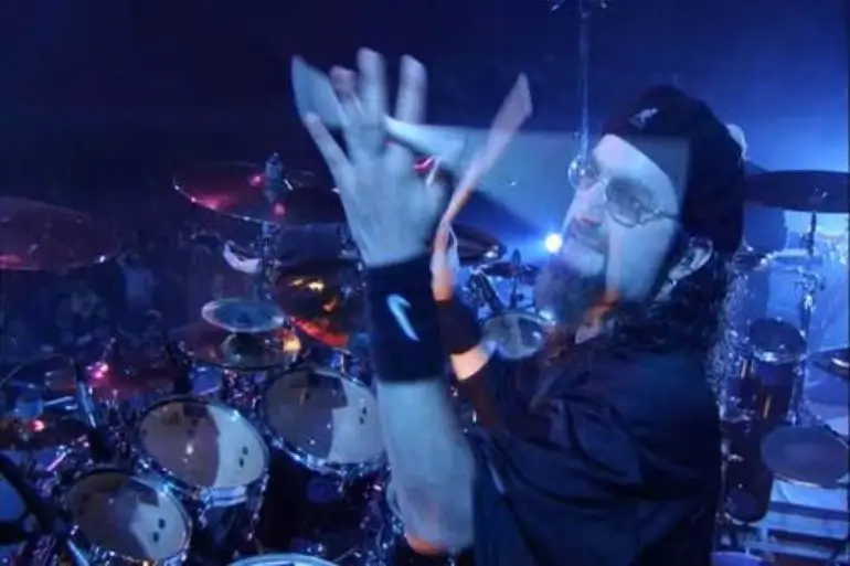 Mike Portnoy tossing drumsticks in the air during a live performance.